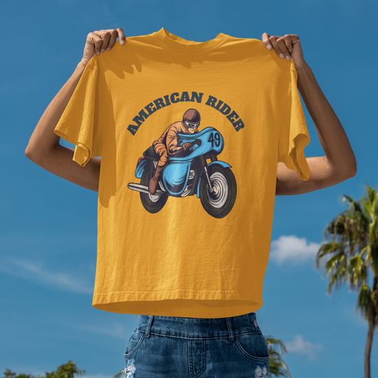 Model holding golden yellow oversized unisex t-shirt with "American Rider" graphic – Thodacrazyclub