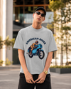 Model wearing grey melange oversized unisex t-shirt with "American Rider" graphic – Thodacrazyclub